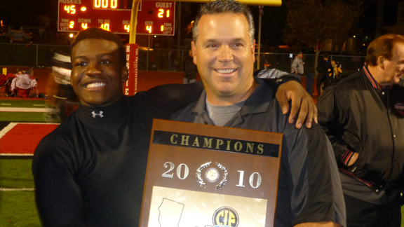 Corona Centennial head coach Matt Logan poses with one of the seven CIF Southern Section championship plaques the program has won under his direction. The Huskies are going for their first in the Pac-5 Division this season.