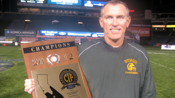 Head coach Dave White from Edison of Huntington Beach shows off hardware won by his team Friday night at Anaheim Stadium. The Chargers topped Villa Park for the CIFSS Southwest Division title.
