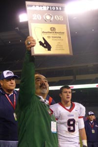 Head coach Raul Lara of No. 6 Long Beach Poly holds up one of the CIF Southern Section titles that he has won while leading the program. Photo: Mark Tennis.