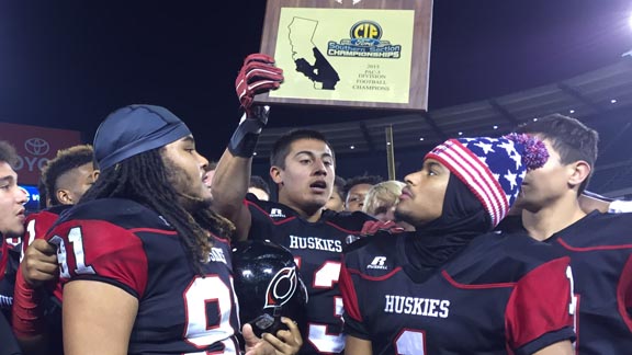 Corona Centennial's Chacho Ulloa holds up 2015 CIFSS title plaque while Noah Anthony (left) and Cameron Jackson (right) look on amid other teammates. Huskies scored unbelievable 55 points in first half. Photo: Mark Tennis.