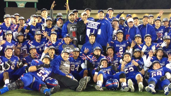 Folsom players and coaches hold up four fingers to signify team winning four straight CIF Sac-Joaquin Section blue banners. Photo: Paul Muyskens